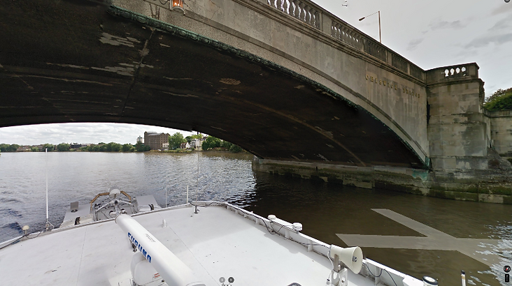 Top Gear Series 10 Episode 5 - Jeremy in his red power speed boat under Chiswick Bridge on the river Thames with the city of London in the background.