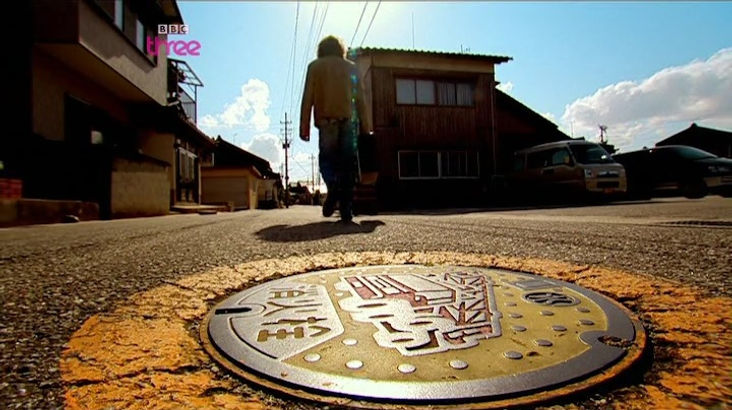 Top Gear Series 11 Episode 4 - A close up of the man hole cover on the street in Hakui, Ishikawa, Japan and James with much excitement mentions how fascinating they are due to the decorative styling they have.