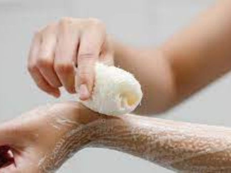 Joven exfoliando su piel con una Lufa.