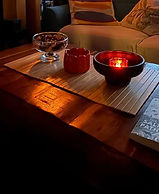 Lit candle in a bowl on a coffee table with a book.