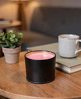 Pink candle in a black tin on a wooden table
