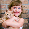 Little girl smiling, holding a ginger tabby cat