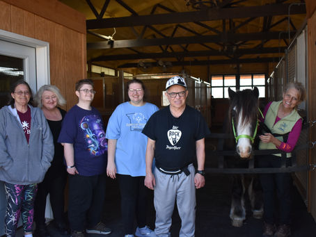 Members of Ride On St. Louis's Helping Hands program smile at the entrance of the barn with service horse Ghost and instructor Marita Wassman.