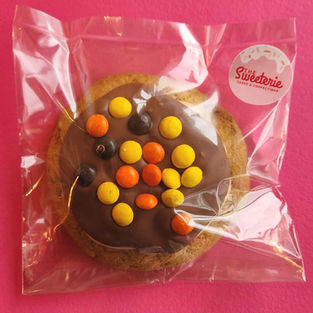 Chocolate cookie with colorful candy, "Süßerie sweets & more" in plastic bag.