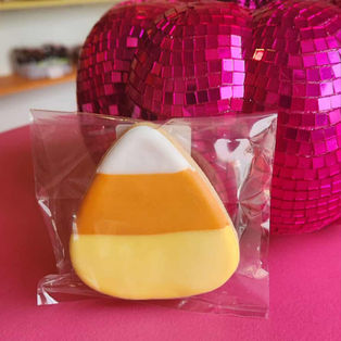 Candy corn shaped cookie, individually wrapped, with pink disco pumpkin background.
