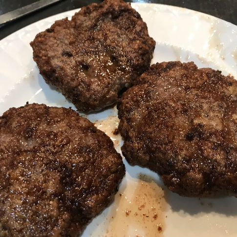 Three grilled beef patties on a plate