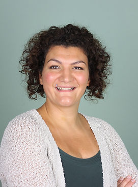 Porträt von Nadia Untersander, Gründerin von mentalesPLUS, lächelt in die Kamera mit leuchtenden Augen und kinnlangem lockigem Haar, trägt ein graugrünes Top und ein naturbeigefarbenes Bolero, symbolisiert Wärme und Vertrautheit für den Abschnitt 'Meine Geschichte'