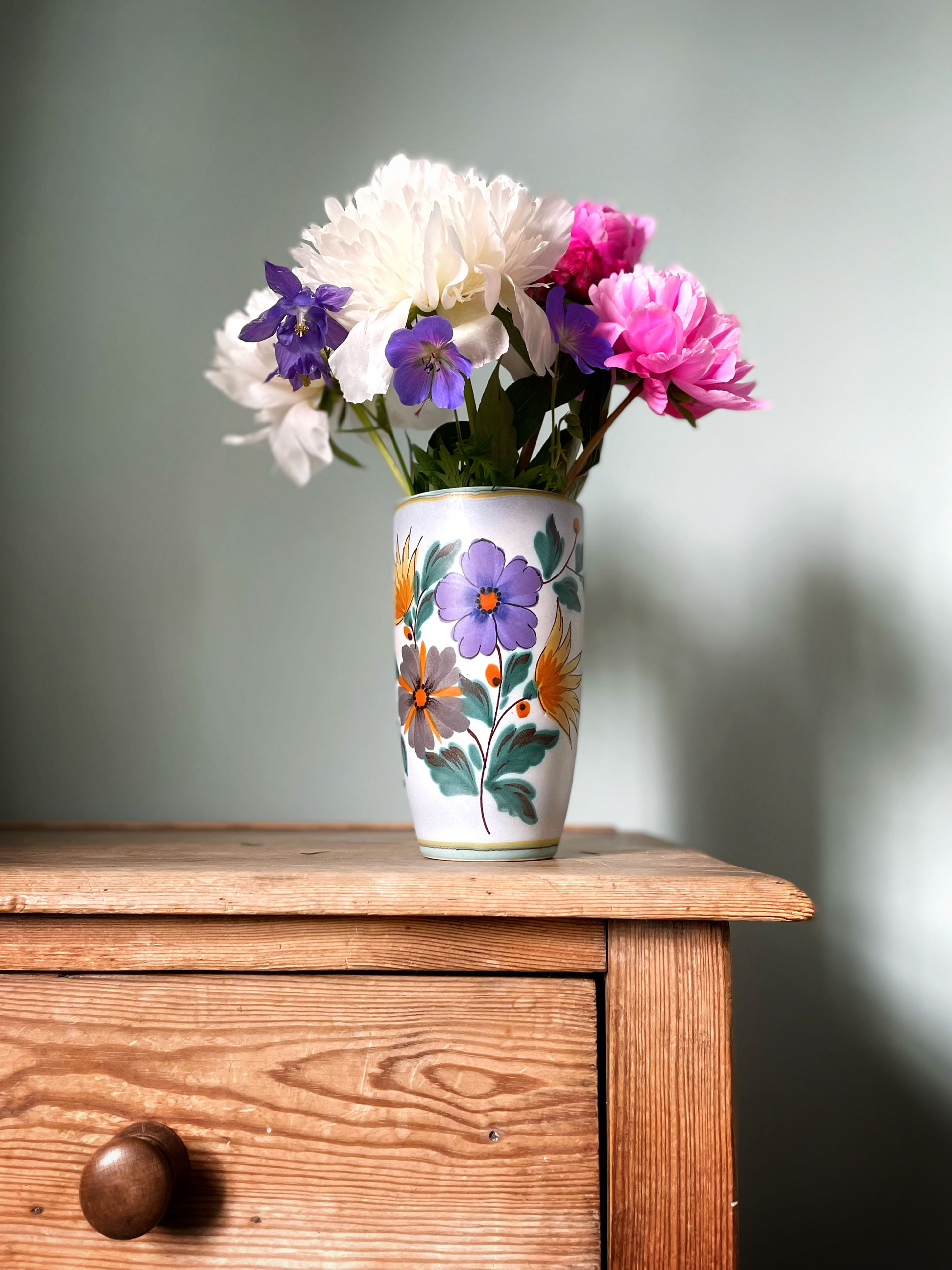 Floral ceramic vase with peonies on table
