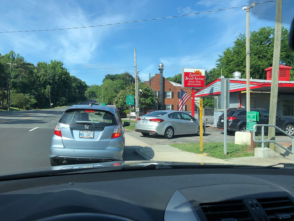 line of cars leading to Sunrise Biscuit Kitchen drive thru with blue sky in background