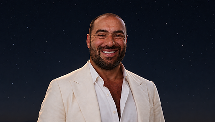 Niko-Helios in an ivory suit beneath a subtle, star-filled night sky