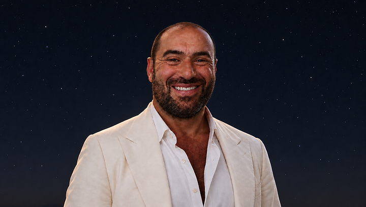 Niko-Helios in an ivory suit beneath a subtle, star-filled night sky