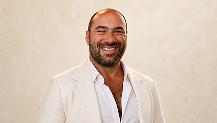 Niko-Helios smiling in an ivory suit against a warm ivory background