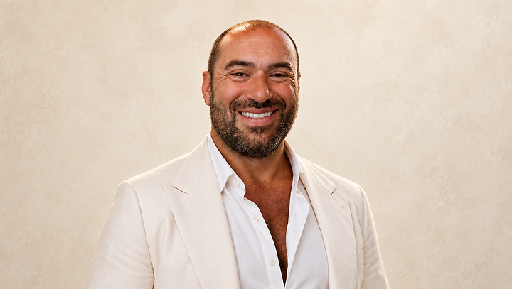 Niko-Helios smiling in an ivory suit against a warm ivory background