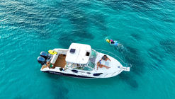 A small boat on the open sea, with clear skies and gentle waves in the background.