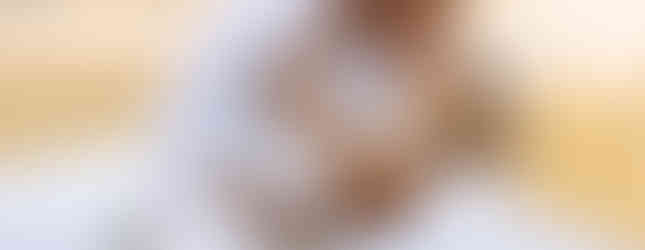 A fiance dips his fiancee in front of a lake in white outfits.