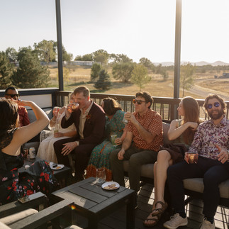 Guests of a wedding sit on the patio of mountain crust event venue sipping cocktails.
