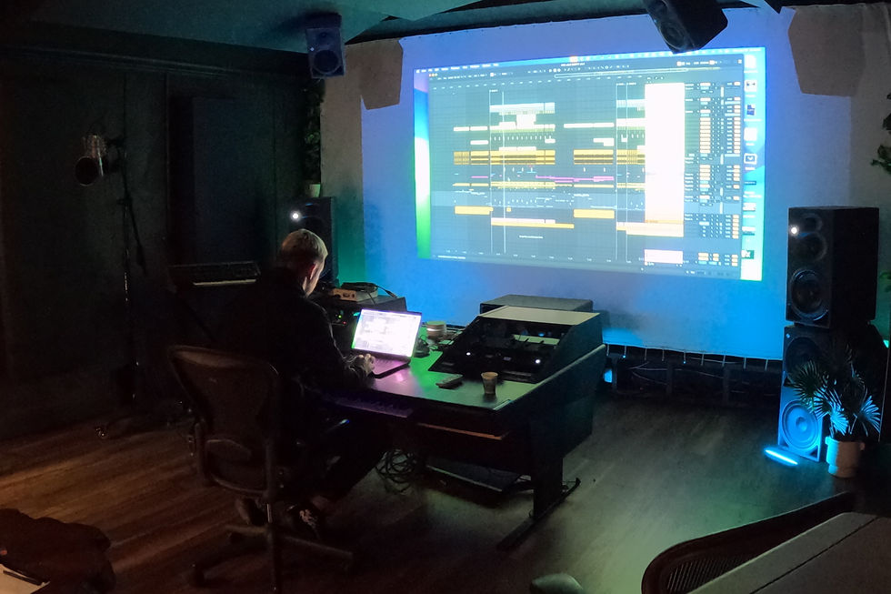 Nevelsky working on new music compositions in the studio, with a large audio project displayed on the screen and surrounded by professional equipment.