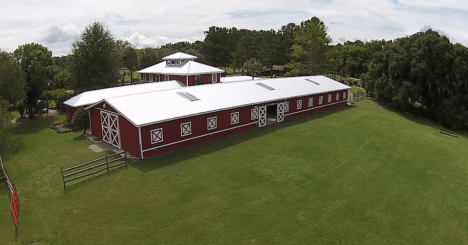 The traditional red door Barn and meadow, a wedding and event venue, at Red Gate Farms with waterfront views
