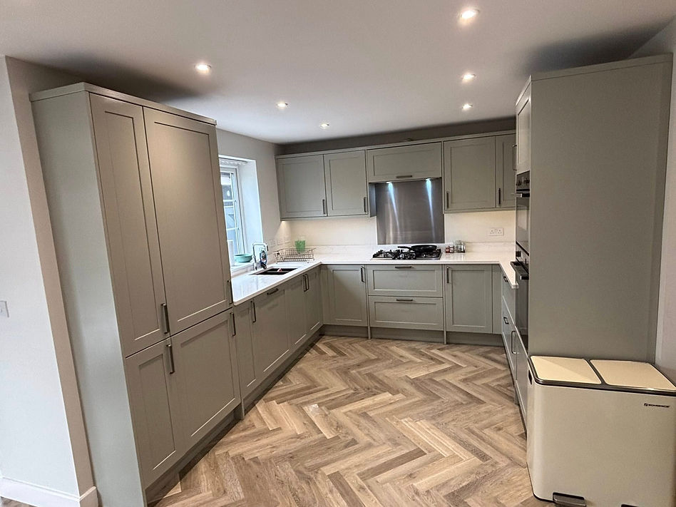 Modern kitchen with light gray cabinets, herringbone wood-patterned floor, a gas stove,