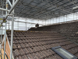 Temporary scaffold roof installed above pitched residential roof with tiled surface visible below.