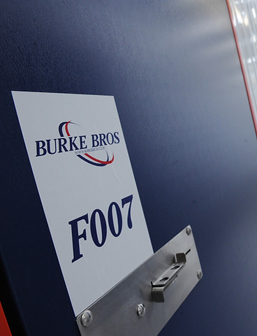 Burke Bros Moving and Storage branded identification label F007 on a navy blue storage container