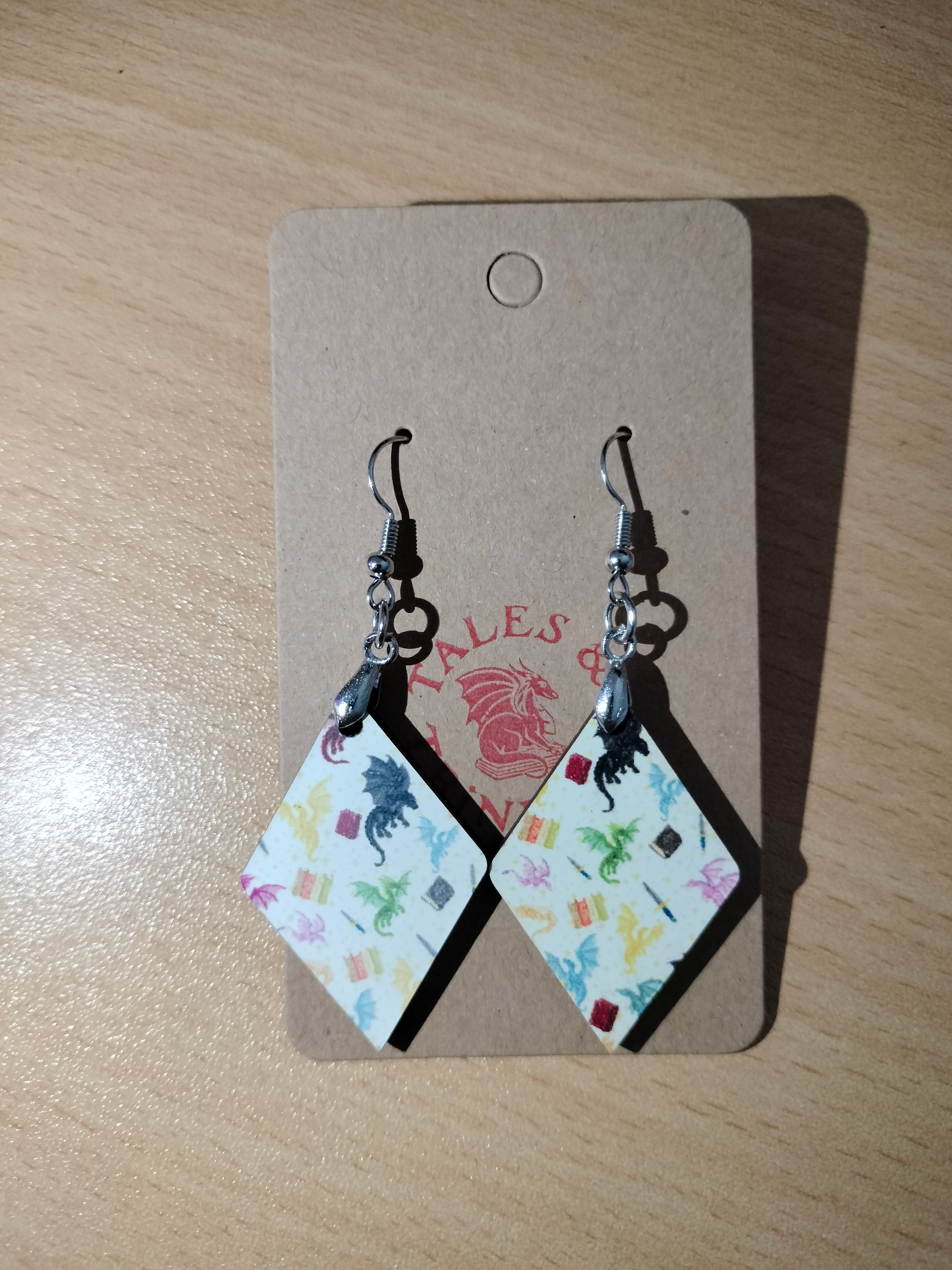 Dragon earrings in a diamond shape made from mdf and on a brown earring backing