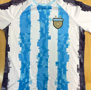 Argentina-style soccer jersey with pixelated sky-blue and white stripes, crest, and two stars, custom shirt nyc sample on wooden table. At Wow! Custom Tees