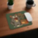 Funny Christmas cat mousepad on wooden desk with coffee cup and small plant.