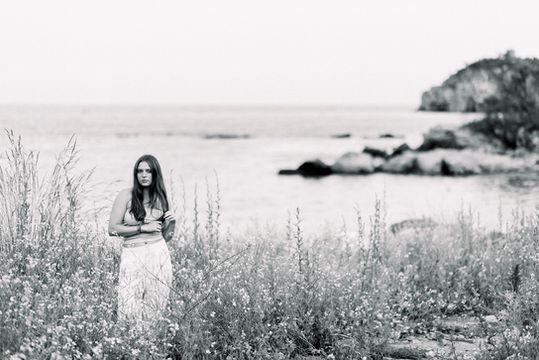Tallulah in a filed of yellow flowers with ocean behind 