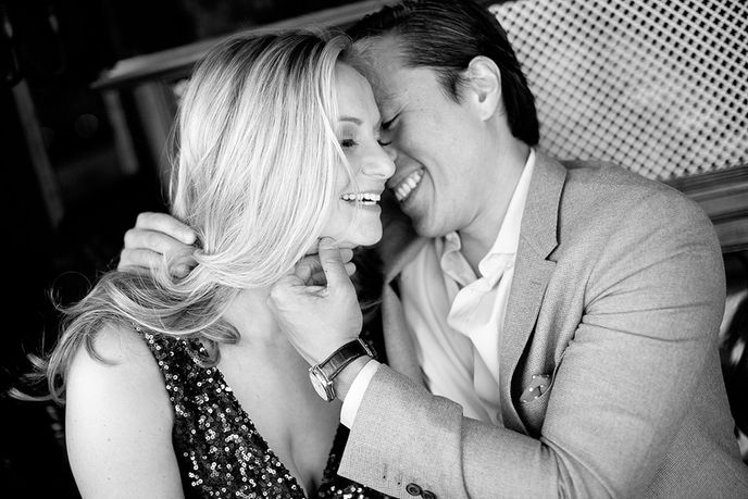 white woman and Asian man whispering sweet nothings by Julie Weisberg engagement photographer,