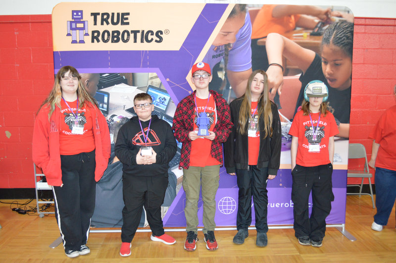 Winning teams proudly hold their trophies, smiling and celebrating their achievements at the robotic