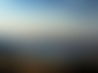 Serene mountain lake at sunset, snowy peaks reflected in calm water under a blue-and-gold cloudy sky.