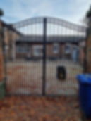 Black wrought iron double gate at the entrance of a residential driveway, galvanized and powder-coated for low maintenance