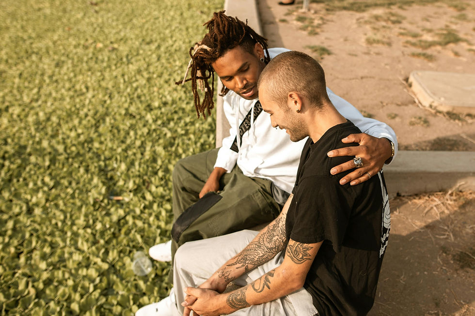 two people sit side-by-side. one has their arm around the other.