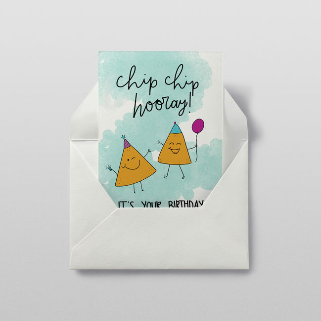 An illustration of two tortilla chips with birthday hats and a balloon, and text above them that says "chip chip hooray" and text that says "It's your birthday!", shown on a card sticking out of an envelope.