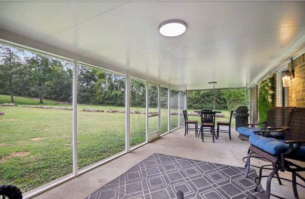 Screened porch with outdoor dining set and sitting area overlooking yard.