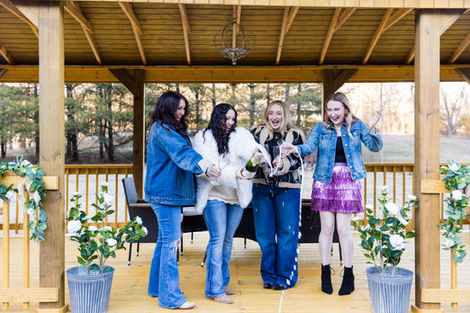 Four happy young women celebrating inside a beautiful wooden gazebo.