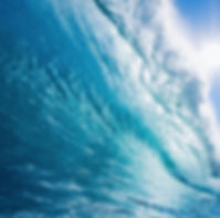 Powerful blue ocean wave, light shining through