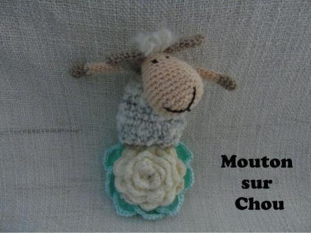 Mouton crocheté sur fond gris, posé sur un chou blanc et turquoise, avec le texte Mouton sur Chou.