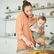 Mère qui tient son bébé tout en préparant à manger et en téléphonant
