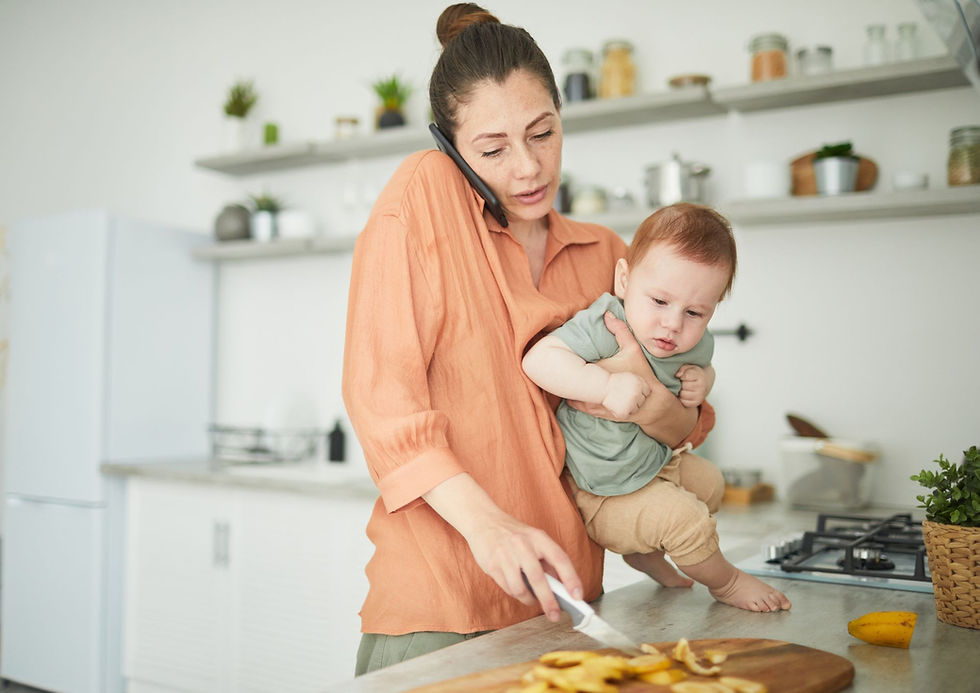 Mère qui tient son bébé tout en préparant à manger et en téléphonant