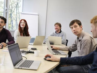 Mitarbeitende von eMoSys sitzen gemeinsam an einem Besprechungstisch und tauschen sich in einer Teamrunde aus. Das Foto zeigt die Zusammenarbeit und den fachlichen Austausch hinter der Entwicklung innovativer elektrischer Antriebssysteme.