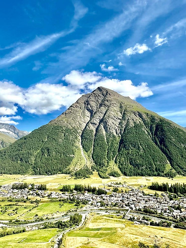 Paysage d’été à Bessans, avec prairies verdoyantes et montagnes de Haute-Maurienne sous un ciel bleu.