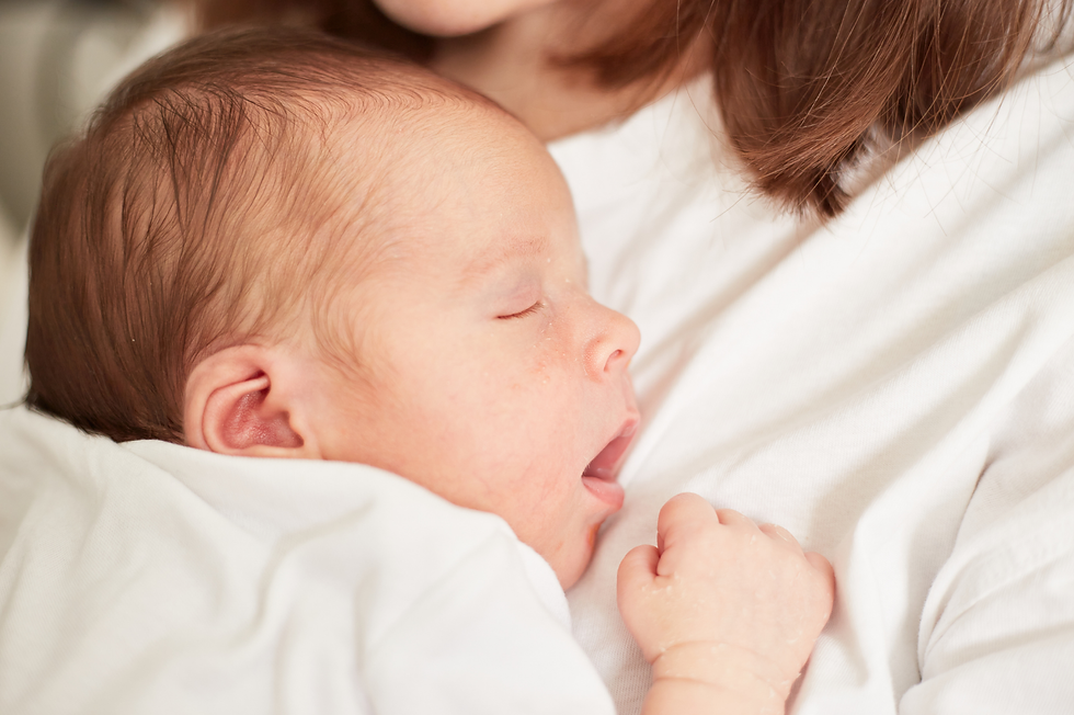 Sleeping newborn resting against a mother’s white shirt, close-up in soft light, peaceful and cozy