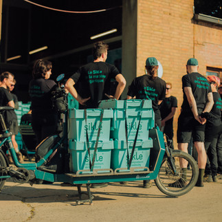 Réunion d'équipe des siklistes, un vélo-cargo bili800 chargé de bacs au premier plan