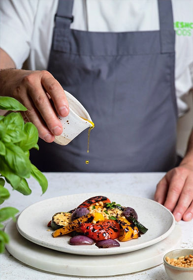 Chef pouring olive oil over chargrilled vegetables