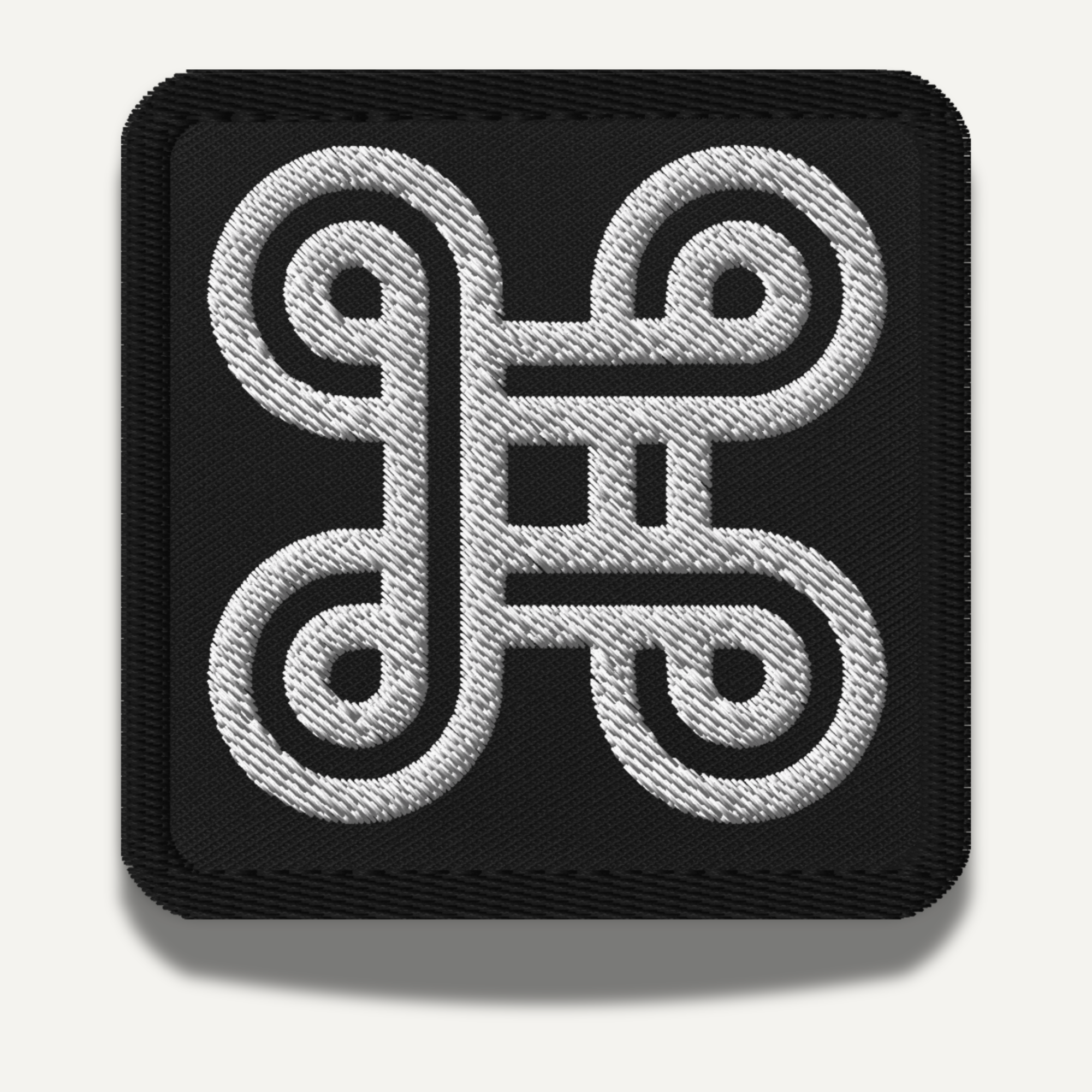 Mpatapo Adinkra embroidered patch symbolizing reconciliation, peace, and unity in black and white.