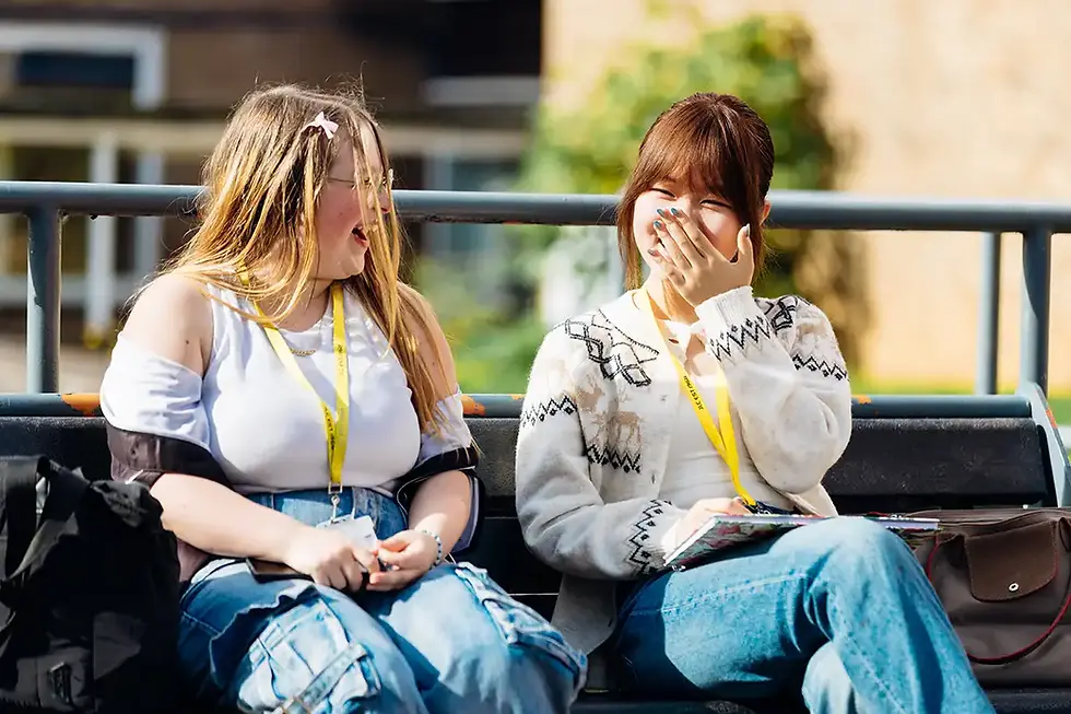 Two John Leggott College students sitting on a bench outside laughing as part of the international buddy scheme