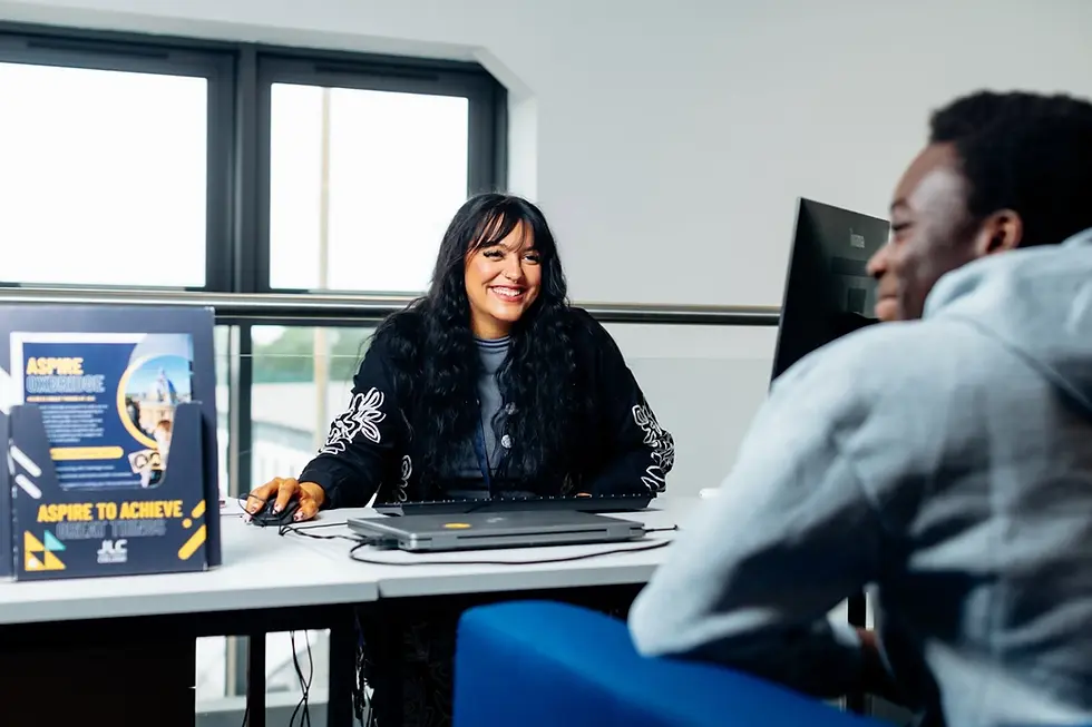 Student and staff member of mixed gender and ethnicity sitting at a desk in a bright study area at John Leggott College, Scunthorpe, North Lincolnshire, reviewing a UCAS application.