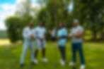 Four men with golf clubs standing on a green course.